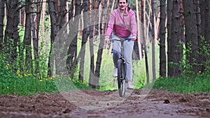 Young Woman on a Bicycle Rides Along a Forest Path in Summer Day, Slow Motion