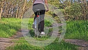 Young Woman on Bicycle Rides Along Green Forest Path in Summer Day, Slow Motion