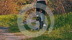 Young Woman on Bicycle Rides Along Green Forest Path in Summer Day, Slow Motion