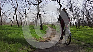 Young Woman on a Bicycle Rides Along a Path in the Forest in a Sunny Spring Day