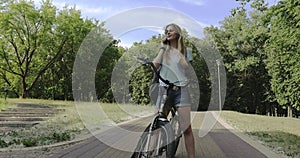 Young woman with bicycle talking on mobile phone outdoors.