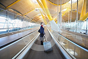 Young woman with big travel bag stands in hallway