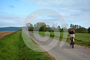 Young woman on a bike rides on a lonely country road in green nature