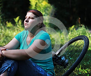Young woman on bike standing on road and looking to somewhere