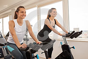 Young woman biking in the gym, exercising legs doing cardio wor