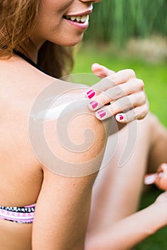 Young woman in bikini applying sunscreen