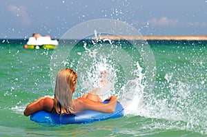 Young woman in bikini backwards in sea water on swimming circle