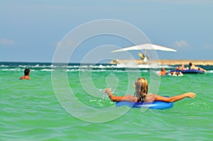 Young woman in bikini backwards in sea water on swimming circle