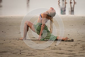 A young woman in a bikini is engaged in yoga on the beach.