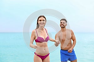 Young woman in bikini with her boyfriend on beach. Lovely couple