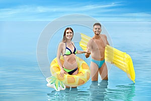 Young woman in bikini and her boyfriend with inflatable toys on beach