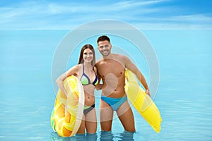 Young woman in bikini and her boyfriend with inflatable toys. Lovely couple