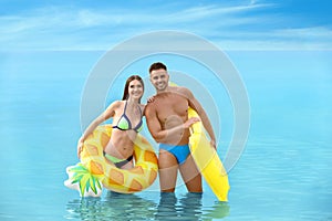 Young woman in bikini and her boyfriend with inflatable toys. Lovely couple