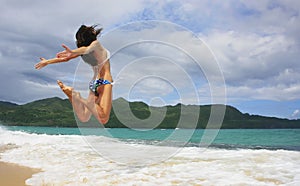 Young woman in bikini jumping at Rincon beach, Samana peninsula