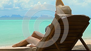 Young woman in bikini lounging on a beach chair, enjoying a luxurious tropical resort