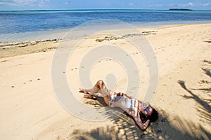 Young woman in bikini lying on the beach on Makaha`a island near photo