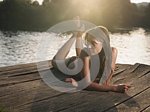 Young woman in bikini lying on jetty looking away