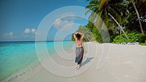 Young woman in bikini and pareo strolls along ocean beach