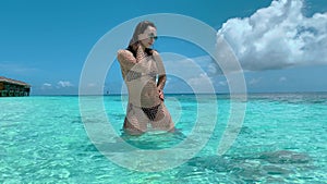 Young woman in bikini poses and enjoys weather near ocean