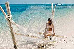 Young woman in bikini relax in hammock at paradise beach. Tropical vacation