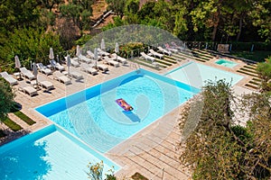 Young woman in bikini air mattress in the big swimming pool