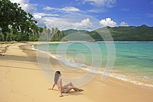 Young woman in bikini sitting at Rincon beach, Samana peninsula