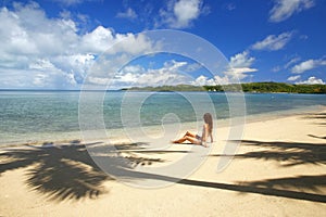 Young woman in bikini sitting on a tropical beach, Nananu-i-Ra i
