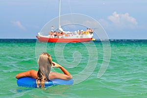 Young woman in bikini standing backwards in sea water with swimming circle