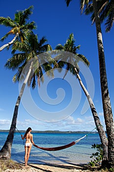 Young woman in bikini standing by the hammock