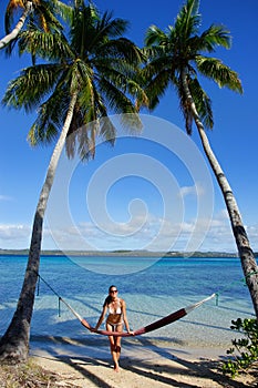 Young woman in bikini standing by the hammock