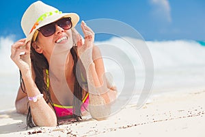 Young woman in bikini and straw hat relaxing at white caribbean beach