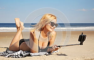 Young woman in bikini taking selfie photo with stick on the beac photo