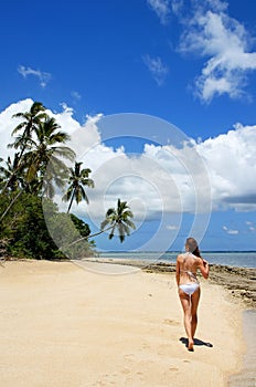 Young woman in bikini walking on the beach at Makaha'a island ne