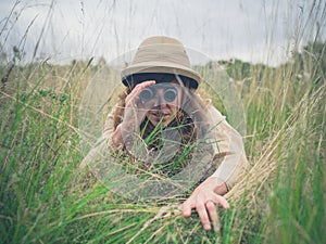 Young woman with binoculars in the grass