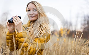 Young woman with binoculars outdoors on fall day