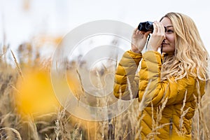 Young woman with binoculars outdoors on fall day