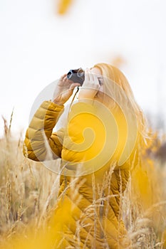 Young woman with binoculars outdoors on fall day