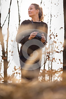 Young woman with binoculars outdoors on fall day