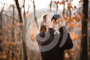 Young woman with binoculars outdoors on fall day