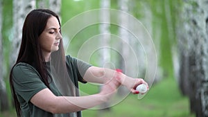 Young woman in a birch grove puts a mosquito repellent on her skin.