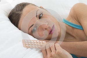 Young woman with birth control pills on bed