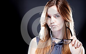 Young woman biting a nerd glasses with interested look