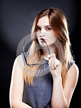 Young woman biting a nerd glasses with interested look