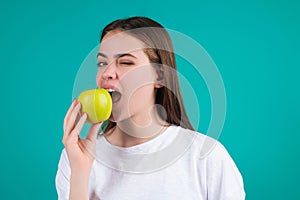 Young woman bitting apple, healthy lifestyle. Girls holds a fresh green apple studio portrait on green isolated