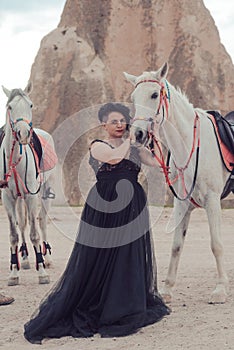 Young woman in black dress with her white horse