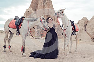 Young woman in black dress with her white horse