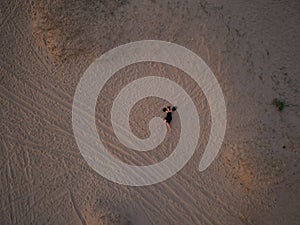 Young woman in a black dress lying on the back on the sand. Top view from the drone