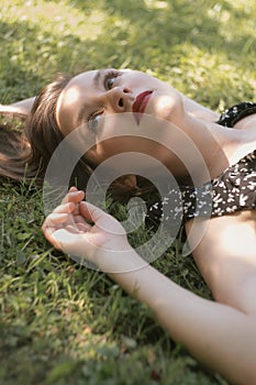 Young woman in black dress lying on green grass