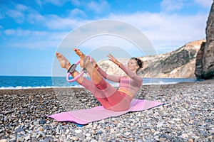 Young woman with black hair, fitness instructor in pink sports leggings and tops, doing pilates on yoga mat with magic