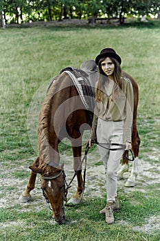 Young woman in black hat with brown horse in countryside. Equestrianism fosters well-being, relaxation. gift certificate for